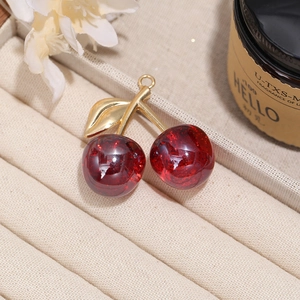 Detailed view of red cherry pendant charm with golden leaf for jewelry making