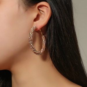 Close-up of oversized gold-plated hoop earrings with sparkling micro-pave crystals on model