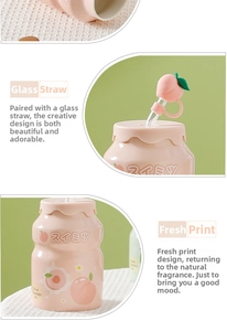 Detail of pink ceramic peach mug with glass straw and silicone peach ornament