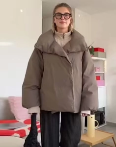 Détail d'une doudoune marron oversize avec un grand col montant et une silhouette ample