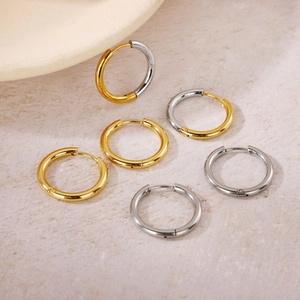 Macro shot of gold, silver, and two-tone mixed color metal hoop earrings on stone background