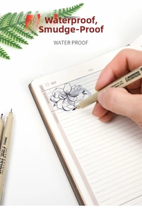 Waterproof drawing pen creating detailed floral sketches on a planner notebook