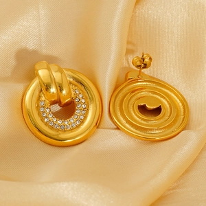 Polished gold round earrings with white zircon accents on smooth satin background