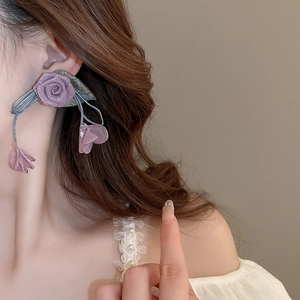 Detailed close-up of a purple mesh rose earring with pearls and flowing fabric petals