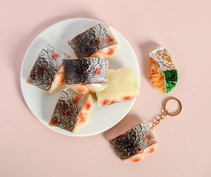 Détails de porte-clés saumon réalistes sur une assiette blanche avec fond rose doux