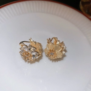 Macro shot of gold floral earrings with opal petals and crystal accents on ceramic
