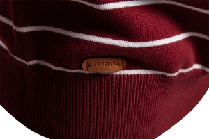 Macro detail of wine red striped knit sweater featuring a brown leather brand label at hem