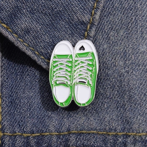Detail of green canvas sneaker enamel pins with black heart on blue denim fabric