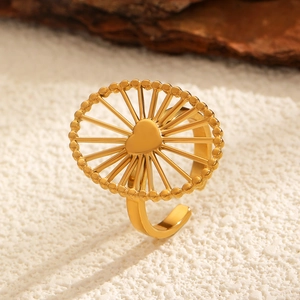 Detailed close-up of golden stainless steel heart ring with sunburst texture and beads