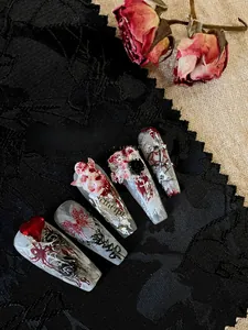 Detailed view of Gothic press-on nails with 3D floral accents on black lace fabric