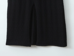 Gros plan de l'ourlet d'une robe en maille noire avec fente latérale et texture fine