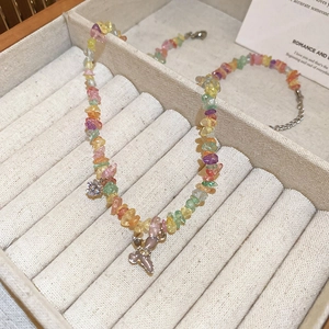 Détail macro d'un collier en pierres colorées avec pendentif papillon rose dans un écrin