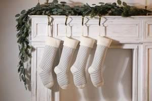 Close-up of four gray and white striped knitted Christmas stockings on a white mantel