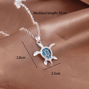 Detail view of a silver turtle pendant featuring sparkling blue opal-like texture and 45cm chain