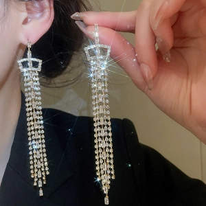 Close-up of golden crown zircon stud earrings with elegant long cascading tassels