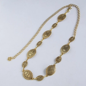 Close-up of bohemian gold metal chain belt with vintage embossed oval plates and hook
