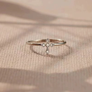 Macro shot of a slim silver cross ring with sparkling crystals on a woven fabric