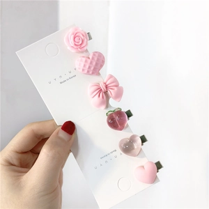 Close-up of pink hair clip set including heart, peach and rose designs on silver clips