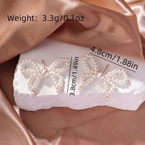 Detailed view of pearl bow earrings with dimensions 4.8cm by 3.8cm and 3.3g weight