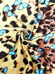 Detail of silk-satin dress fabric with leopard print and vibrant blue butterflies
