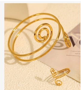 Detail of elegant gold spiral bracelet and matching ring set on a stylish textured surface