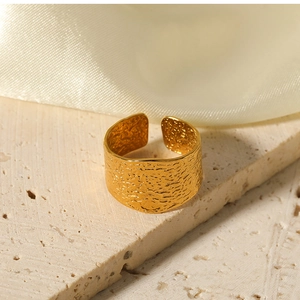 Detailed view of wide golden C-shaped stainless steel ring with hammered texture