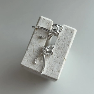 Macro detail of 925 sterling silver bow earrings featuring shimmering zircon accents