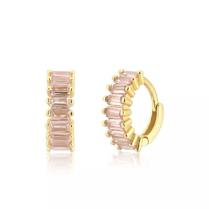 Detail of golden huggie hoop earrings featuring rectangular pink cubic zirconia stones