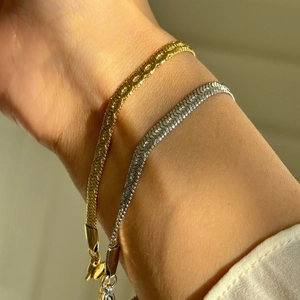 Detailed macro view of gold and silver textured chain bracelets on a woman's wrist