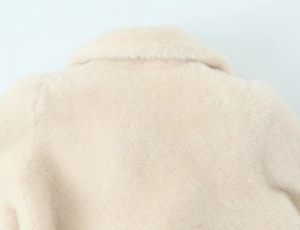 Detailed macro shot of premium cream faux fur texture on the coat collar and shoulders