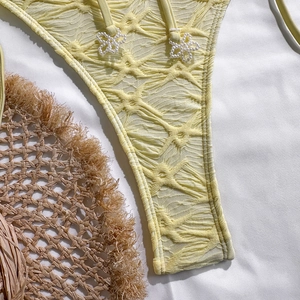 Detail of light yellow bikini bottoms with pleated texture and pearl flower charms
