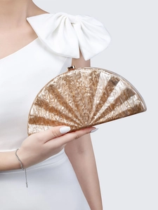 Close-up of gold semi-circle acrylic clutch bag with metal clasp for evening wedding gala