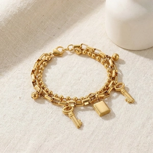 Detailed close-up of double-layer gold chain bracelet with padlock and key charms