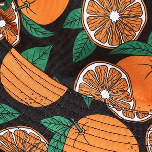 Macro view of vivid orange fruit print on black bucket hat showing fabric texture and seams