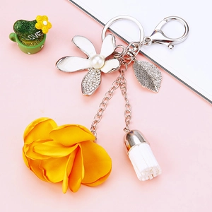 Floral car keychain with white enamel flower, yellow fabric pompom and white tassel