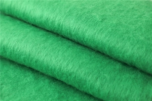 Gros plan sur le tissu mohair vert montrant une texture épaisse et des détails fibreux