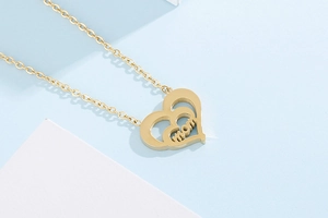 Detail of golden double-layer heart pendant necklace with MOM inscription in the center