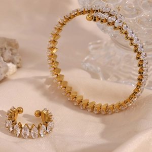 Dettaglio del set bracciale e anello placcati oro con cristalli taglio marquise su seta