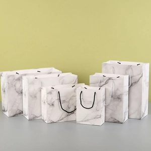 Set of six white marble pattern paper gift bags in various sizes with ribbon handles