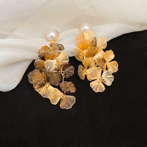 Detail of gold layered flower earrings with white pearl accent on silk background