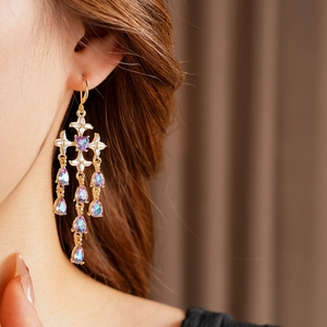 Close-up of golden cross earrings with teardrop crystals worn by a female model