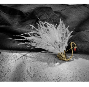 Detailed view of swan brooch with white feathers, pearls and gold finish on stone