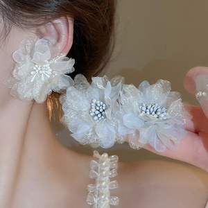 Detail view of large cream mesh flower earrings with delicate white bead centers