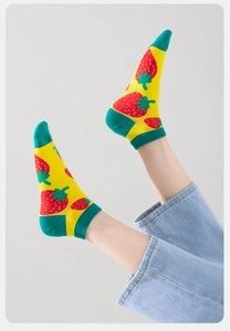 Detailed shot of yellow low-cut socks with cute red strawberry patterns and green heels