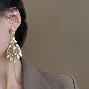 Close-up of champagne crystal drop earrings in a vintage chandelier style on a model