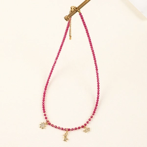 Detailed view of rose red beaded necklace featuring gold star and crown charms