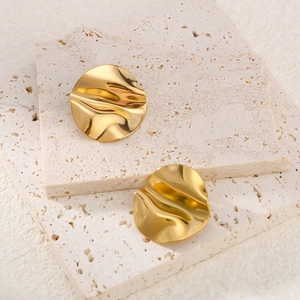 Minimalist gold irregular curved hoop earrings with textured surface on stone display