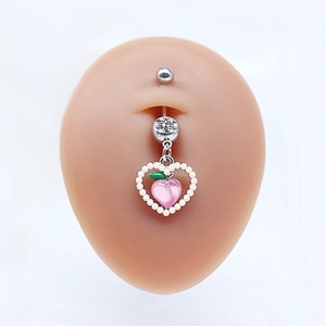 Macro shot of silver navel piercing with peach heart pendant and pearl details