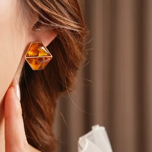Vintage amber resin hexagonal stud earrings with gold trim worn by a model