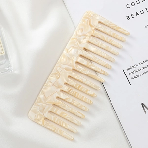 Detailed macro view of ivory marble acetate wide-tooth comb on elegant silk fabric